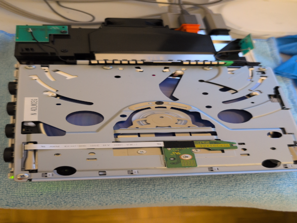 A photograph, of a Nintendo Wii Console running with half the case removed exposing a spinning disc drive for testing.