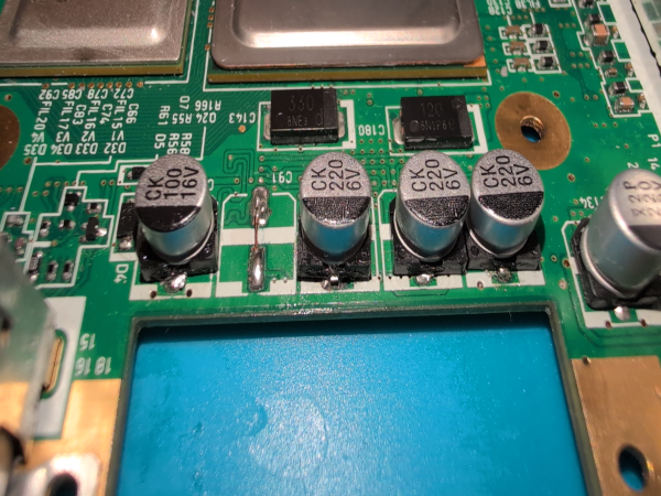 A photograph showcasing replaced video output filter caps on a Nintendo Wii motherboard, the composite one being shorted.